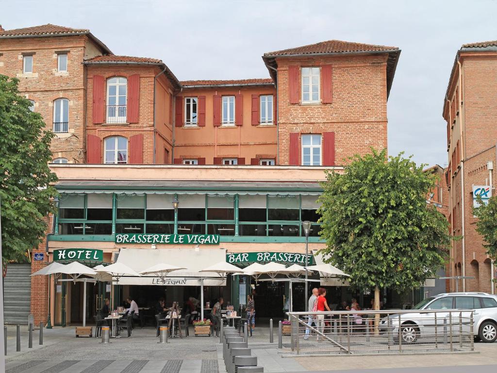 un grand bâtiment en briques avec des personnes assises à l'extérieur dans l'établissement Hôtel du Vigan, à Albi