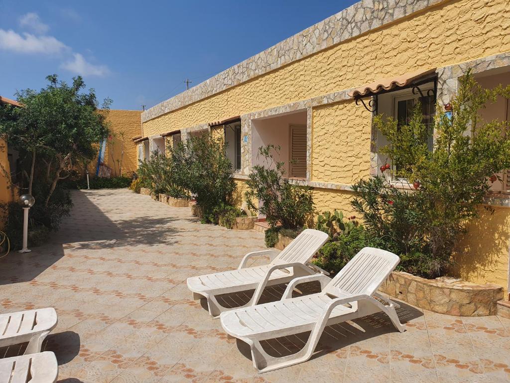 2 sillones blancos sentados junto a un edificio en Residence Villa Felice, en Lampedusa