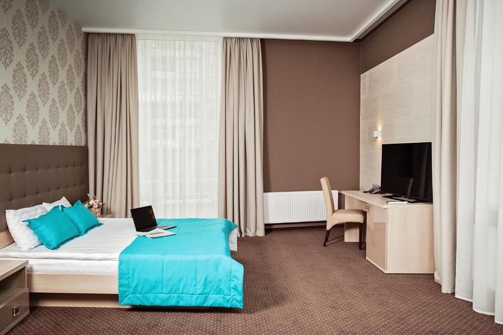 ルツカイにあるHotel Versaillesのベッド、デスク、ノートパソコンが備わるホテルルームです。
