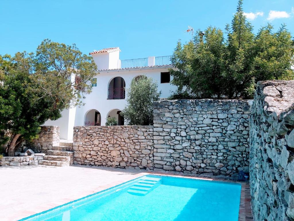 Villa con piscina y pared de piedra. en CASA NICOLE Naturaleza, Montañas y Piscina Privada en Alicante, en Carroja