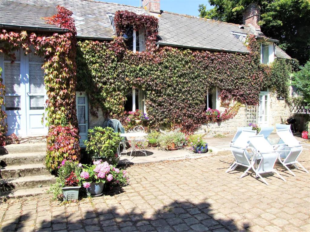 une maison recouverte de lierre avec des tables et des chaises dans l'établissement Le Glycine a Manoir Sainte Cecile, à Juvigny-sous-Andaine