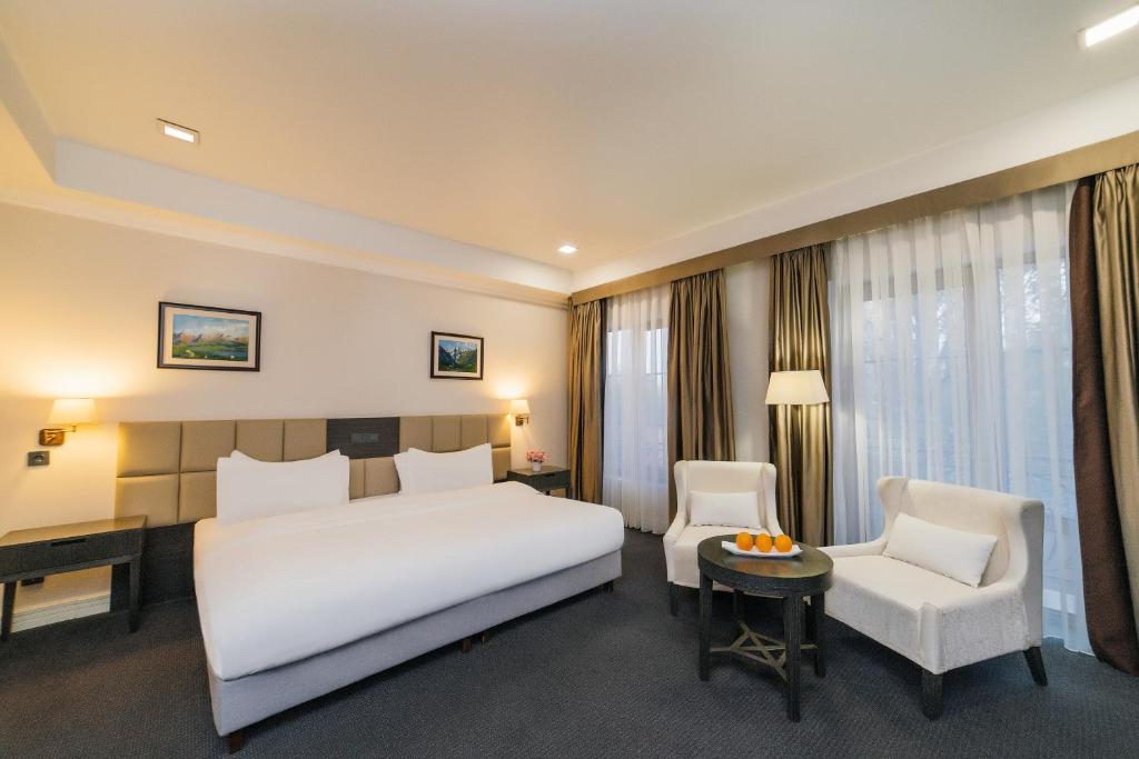 a bedroom with a large white bed and a chair at Ambassador Hotel in Bishkek