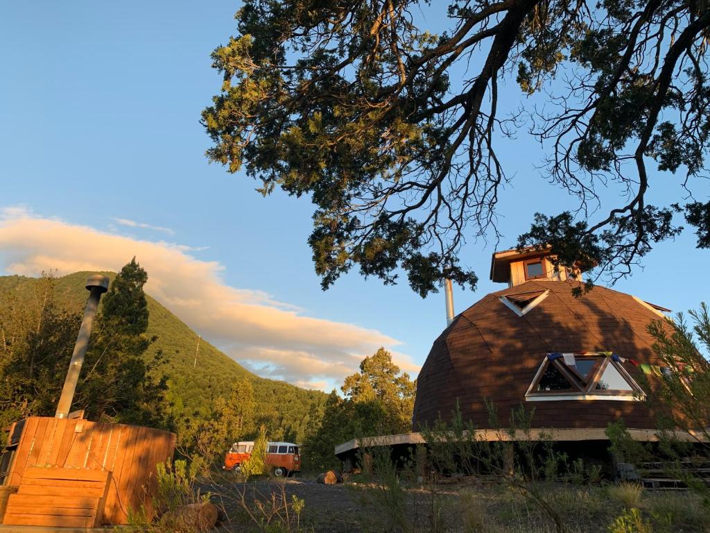 una gran casa en la cúpula con un camión en el fondo en Domo Conguillio Conecta con tu energía sagrada junto al Salto Truful Truful con una vista majestuosa que podrás disfrutar en una tinaja Una experiencia que alineará tu espíritu y tu energía interior Vívelo, en Melipeuco