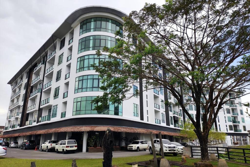 un gran edificio blanco con coches estacionados frente a él en Cozzyhome@REX BDC, en Kuching