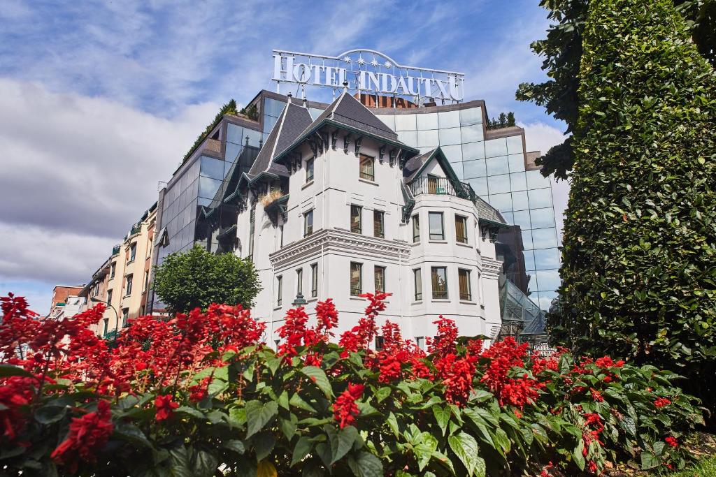 a white building with red flowers in front of a building at Hotel Silken Indautxu in Bilbao