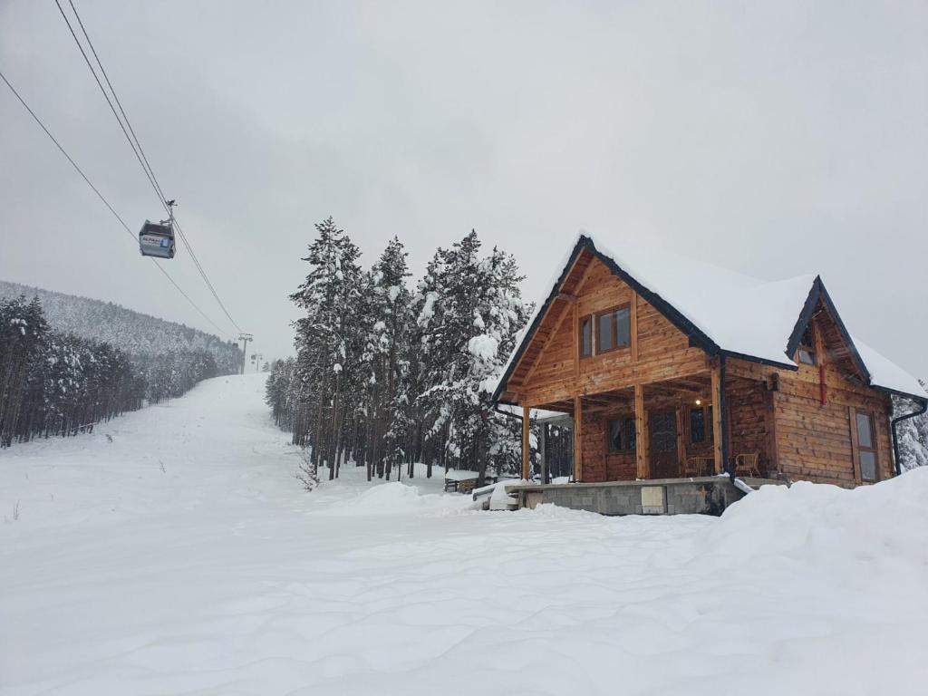 a log cabin in the snow with a ski lift at Tornik Brvnara Ljubojevic in Tornik