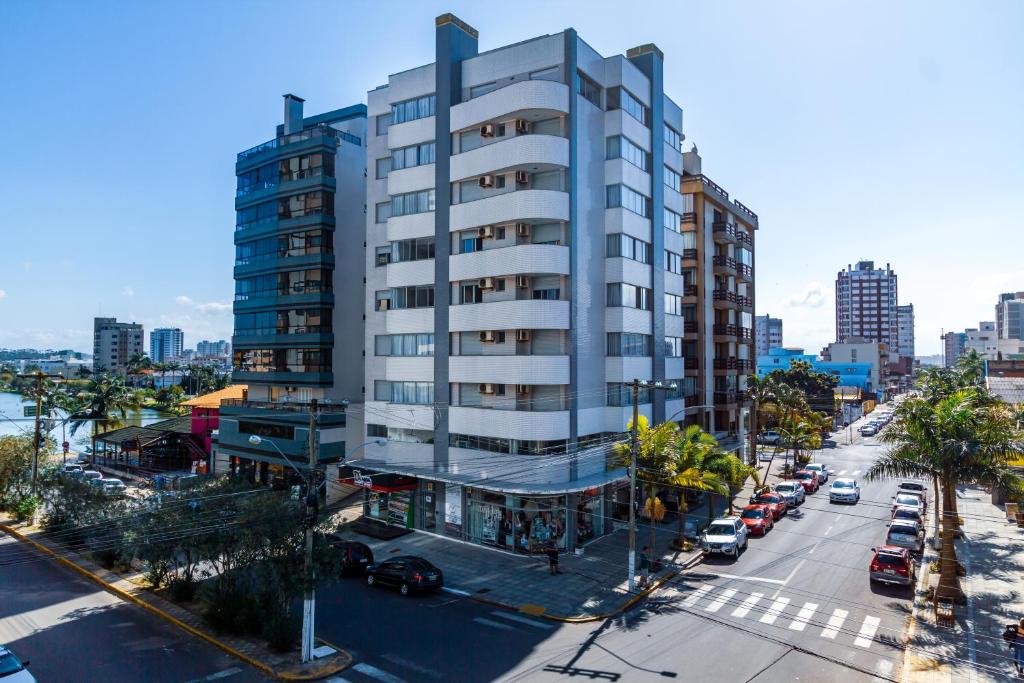 un grand bâtiment blanc dans une rue de la ville avec des voitures dans l'établissement A Furninha Suites, à Torres