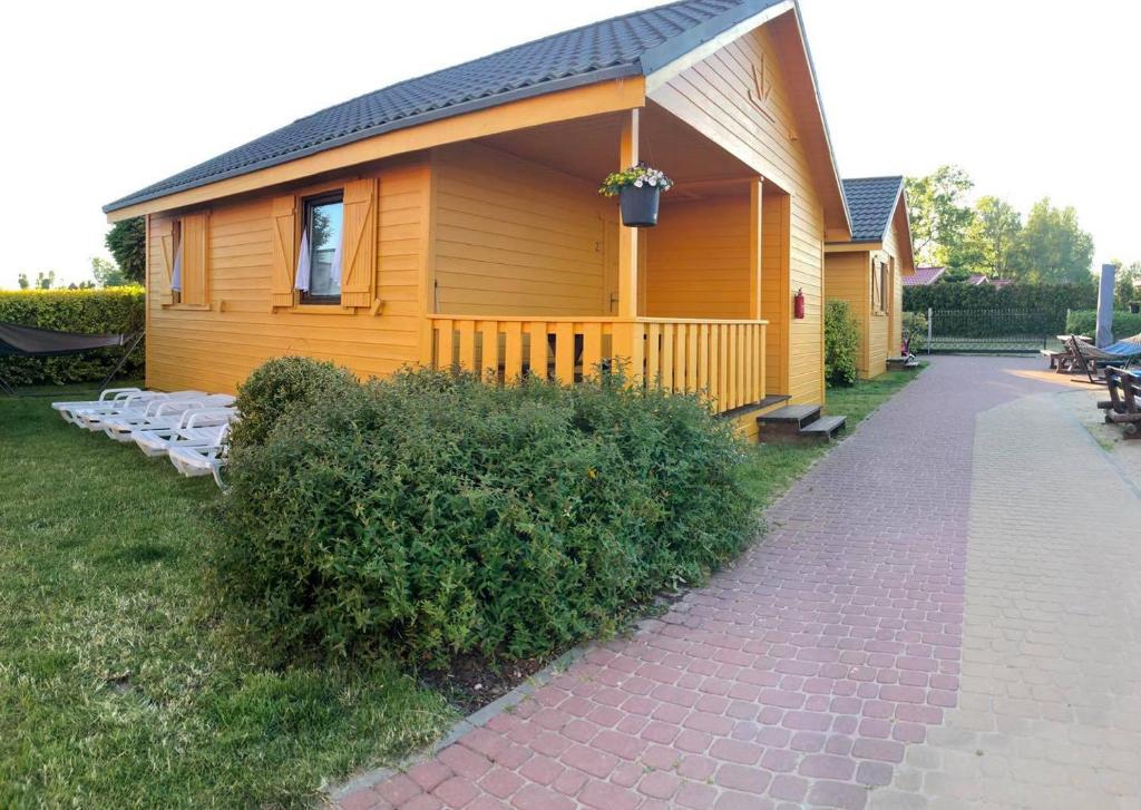 a small yellow house with a pathway next to it at Domki u Małgosi in Rusinowo