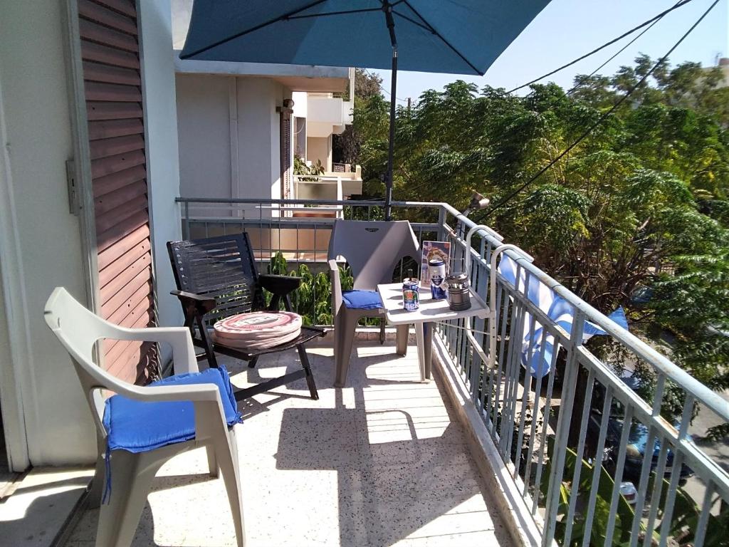 uma mesa e cadeiras numa varanda com um guarda-sol em Apollon Apartments H-3 H-4 in Ilha de Rhodes
