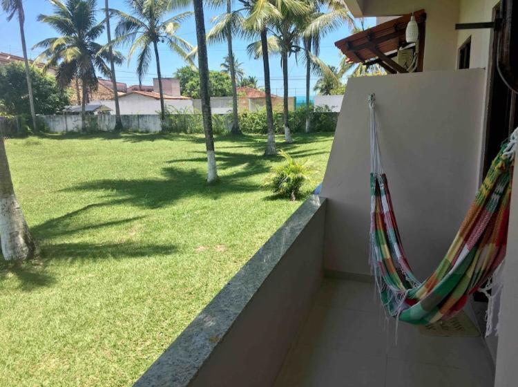 a balcony with two hammocks and a yard with palm trees at Apartmento em Praia de Guaibim in Guaibim