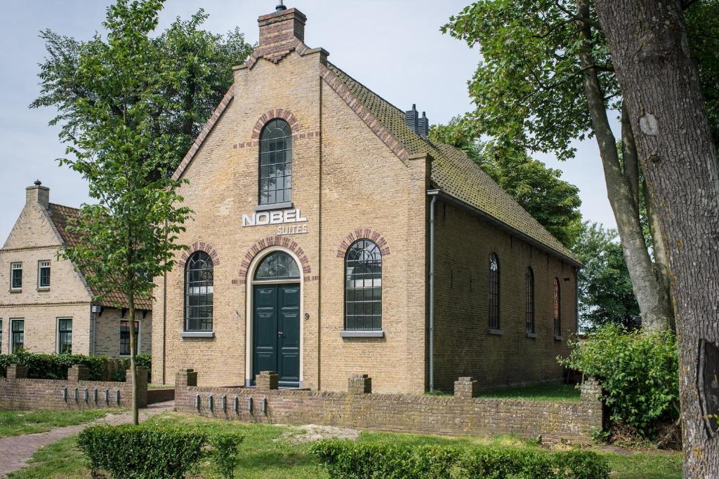 uma velha igreja de tijolos com uma porta verde em Nobel - Suites em Ballum