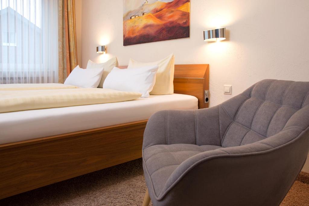 ein Hotelzimmer mit einem Bett und einem Stuhl in der Unterkunft Parkhotel Lippstadt in Lippstadt