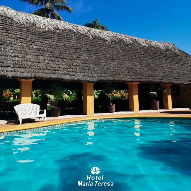 a swimming pool in front of a hotel with a thatch roof at HOTEL MARIA TERESA in Playa Azul