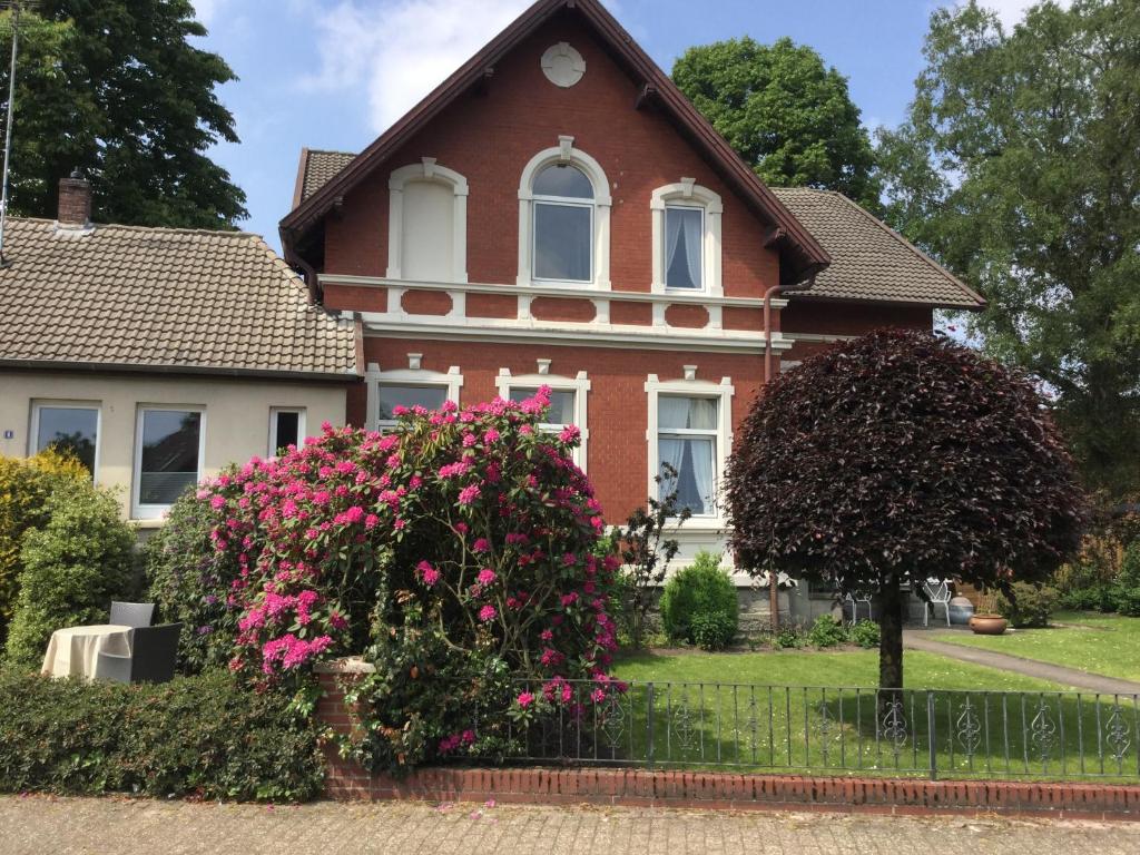 una casa con flores rosas delante de ella en Ferienhaus Us lütt Hus und das Zimmer Linde im Haupthaus, en Oldenburg