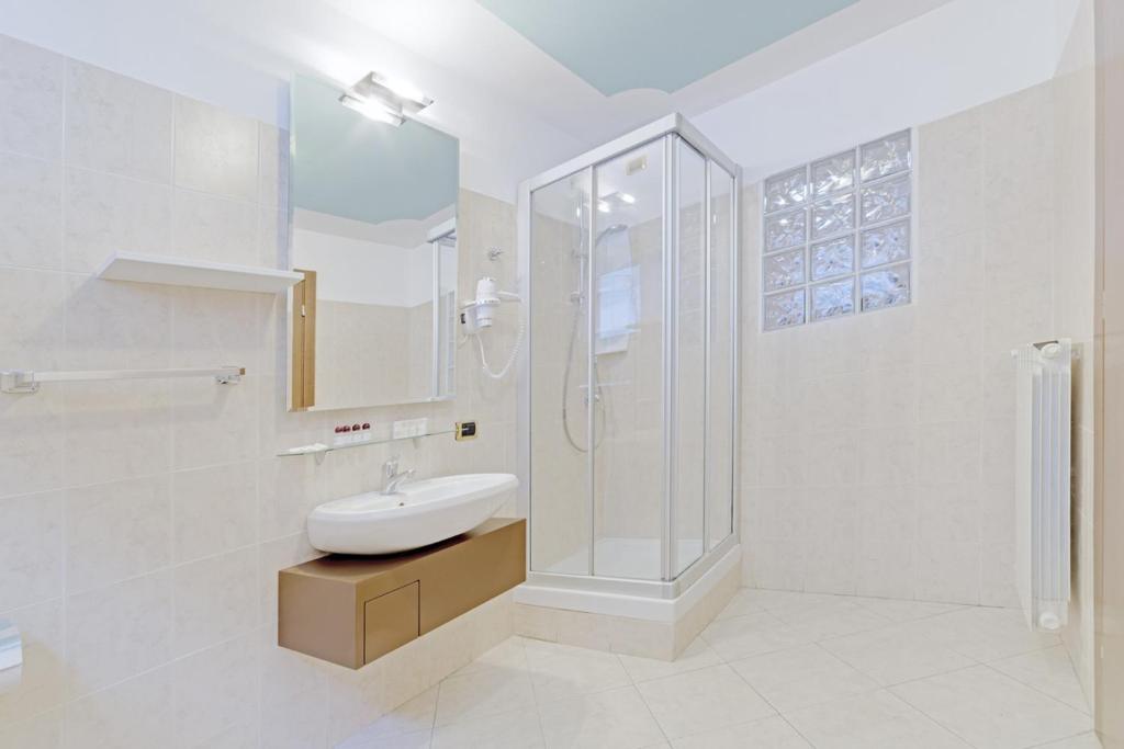 a white bathroom with a sink and a shower at Hotel Grotto Bagat in Lavena Ponte Tresa