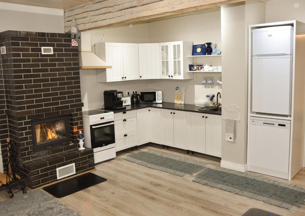 eine Küche mit weißen Schränken und einem gemauerten Kamin in der Unterkunft Paju Apartement with Sauna in Võru