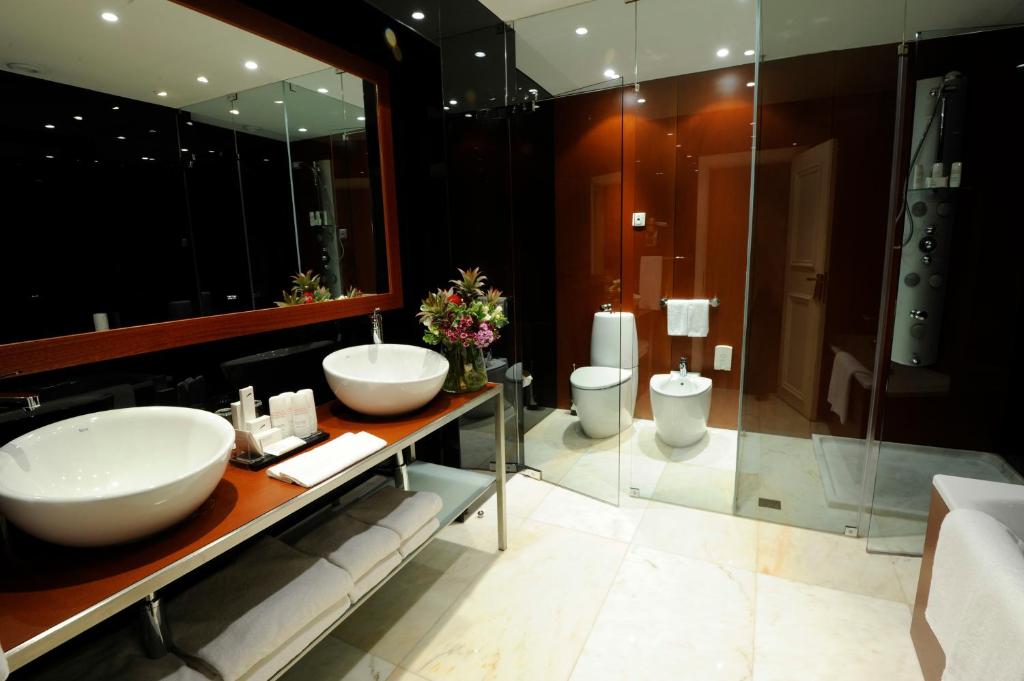 A polished bathroom with twin vessel sinks, a separate toilet and bidet, and a glass shower enclosure.