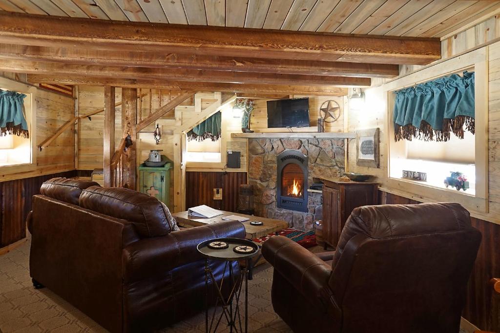 sala de estar con muebles de cuero y chimenea de piedra. en Return to Lonesome Dove, en South Fork