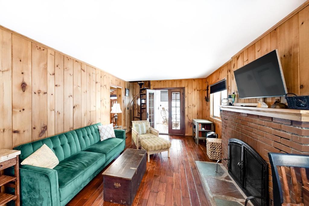 a living room with a green couch and a fireplace at Takundewide Retreat in Lake George