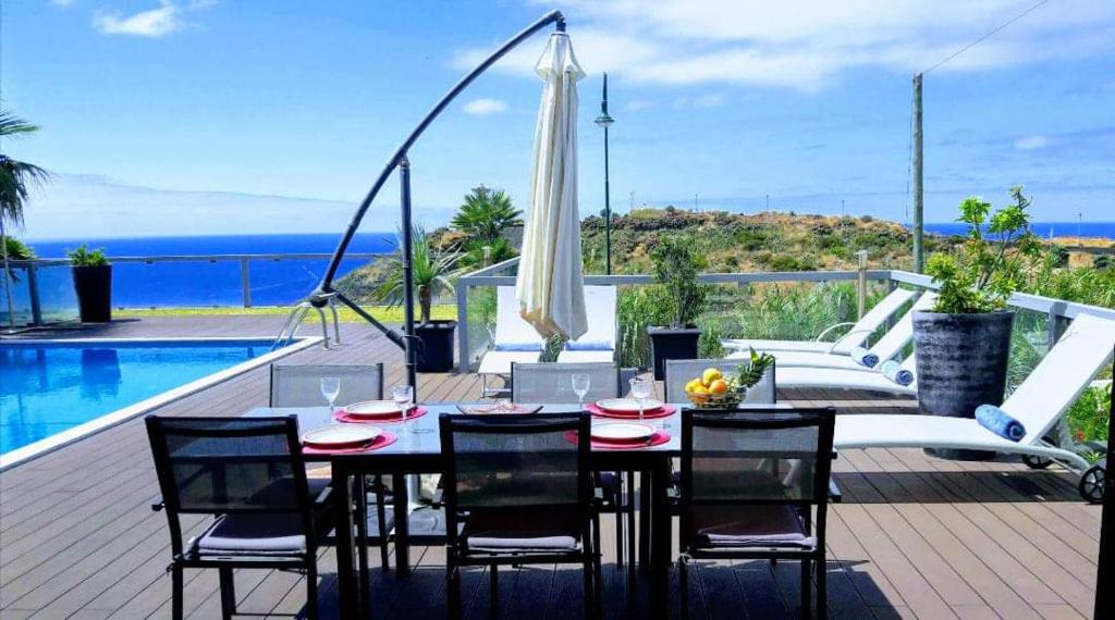un patio con mesa de comedor y sillas y piscina en Villa Sol e Mar Garajau Madeira, en Caniço