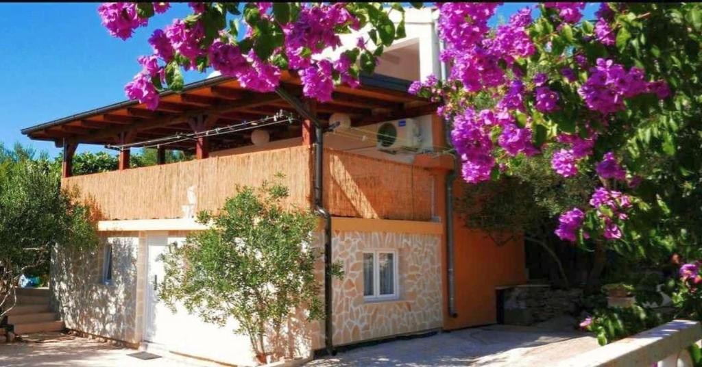 ein Haus mit einem Baum mit lila Blumen in der Unterkunft Island Stone House in Ždrelac