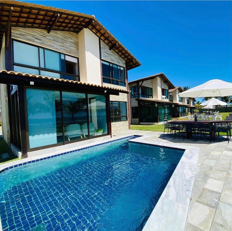 a swimming pool in front of a house at Muro alto Bangalô pé na areia in Porto De Galinhas