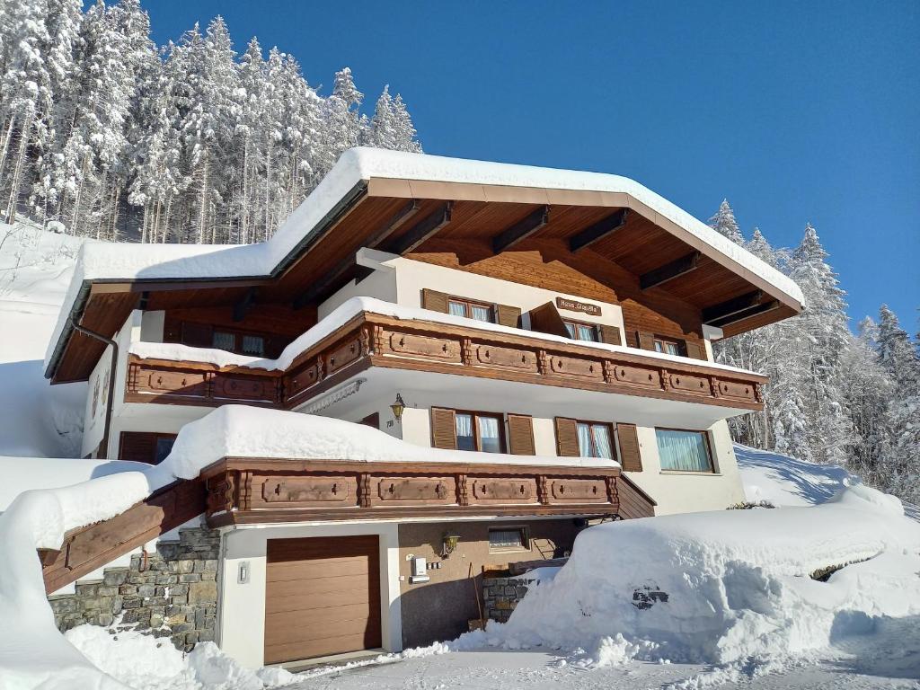 a house covered in snow with trees in the background at Haus Glasella in Schruns-Tschagguns