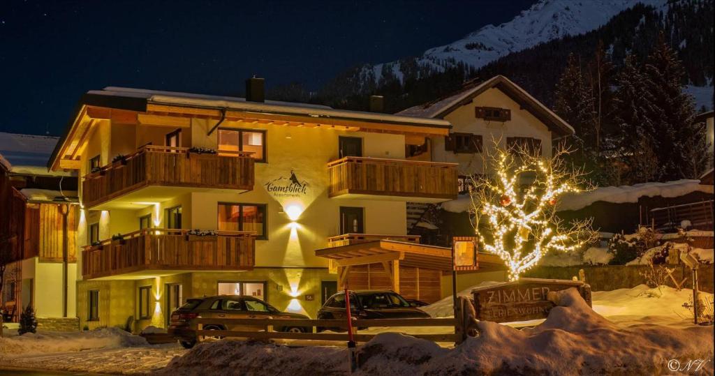 un bâtiment avec un arbre de Noël devant lui dans l'établissement Appartements Gamsblick, à Pettneu am Arlberg