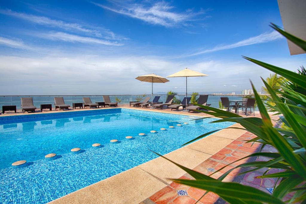 a beach with a pool, chairs, and umbrellas at The Paramar Beachfront Boutique Hotel With Breakfast Included - Downtown Malecon in Puerto Vallarta