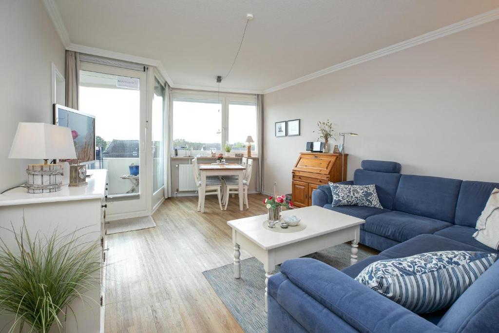 uma sala de estar com um sofá azul e uma mesa em Haus Beau Rivage Wohnung 41 em Scharbeutz