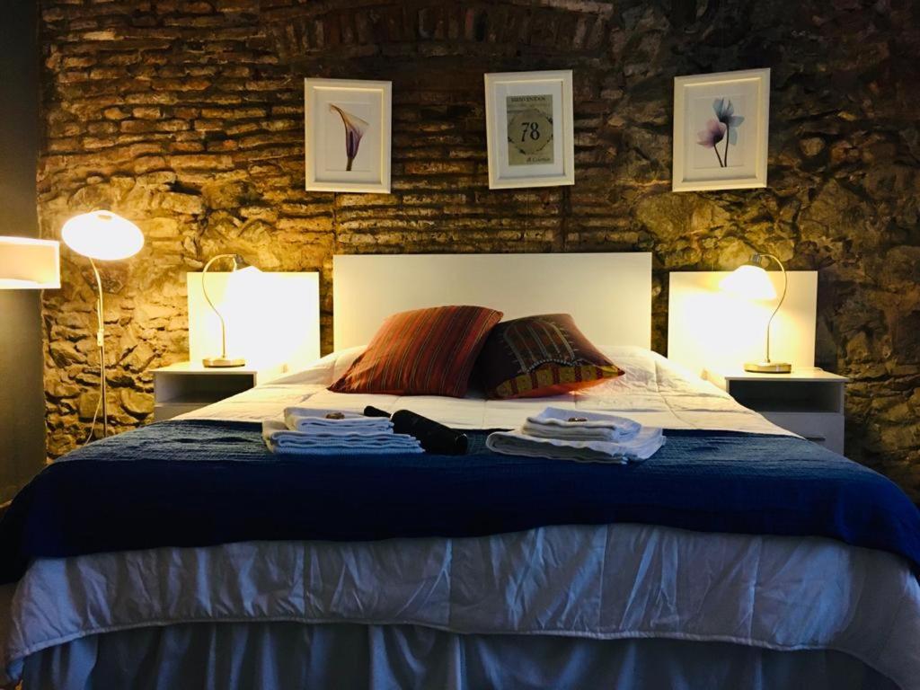 a bedroom with a bed with two lamps and towels on it at Estudio Taller de Tejas Colonia B&B in Colonia del Sacramento