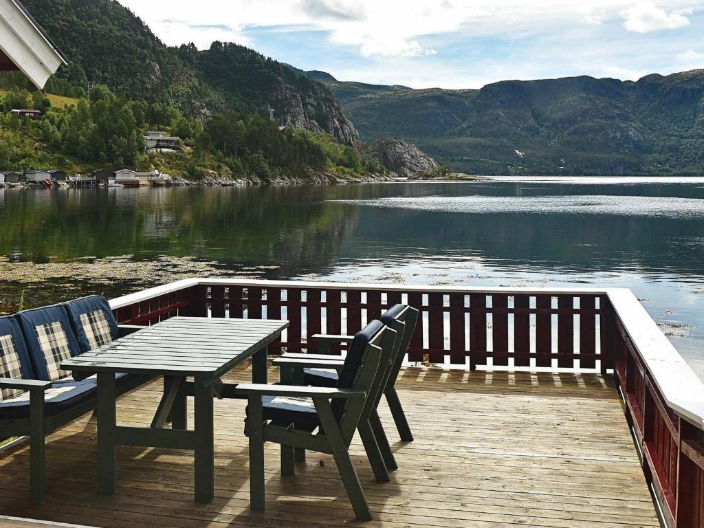 a wooden deck with a table and chairs next to a lake at 8 person holiday home in Sundlandet in Snildal