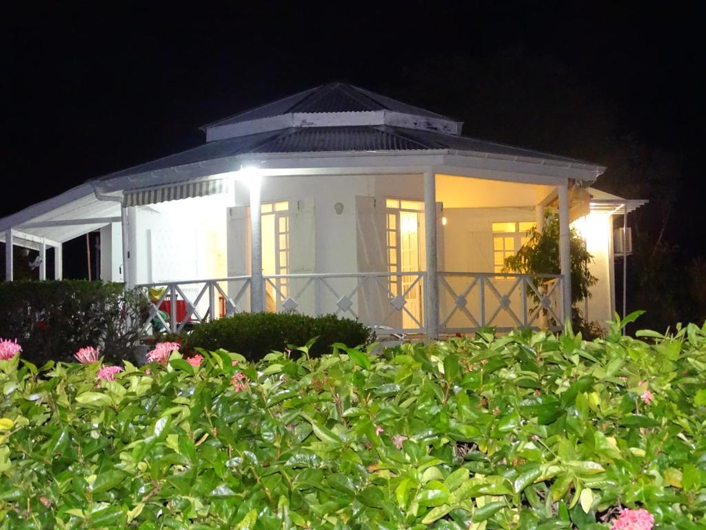 a white house at night with flowers in the foreground at La villa les palmiers simplicité convivialité in Saint-François