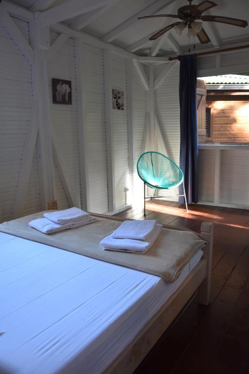 a bed with a blue chair in a room at Les Gîtes de la Lézarde in Petit-Bourg