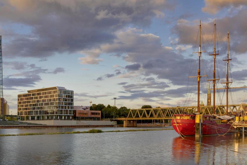 a red boat sitting in the water next to a bridge at Steigenberger Hotel Bremen in Bremen
