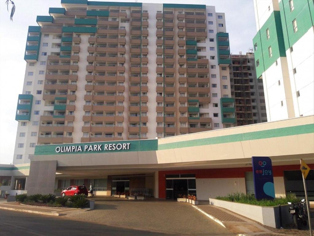 a large building with a parking lot in front of it at OPR - Resort em Olimpia Frente Piscina in Olímpia