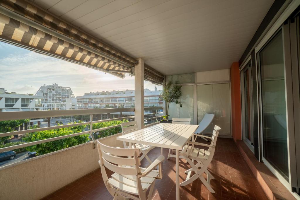 a balcony with a table and chairs and a view at Appartement à quelques pas de la mer WIFI CLIM PARKING in La Grande-Motte