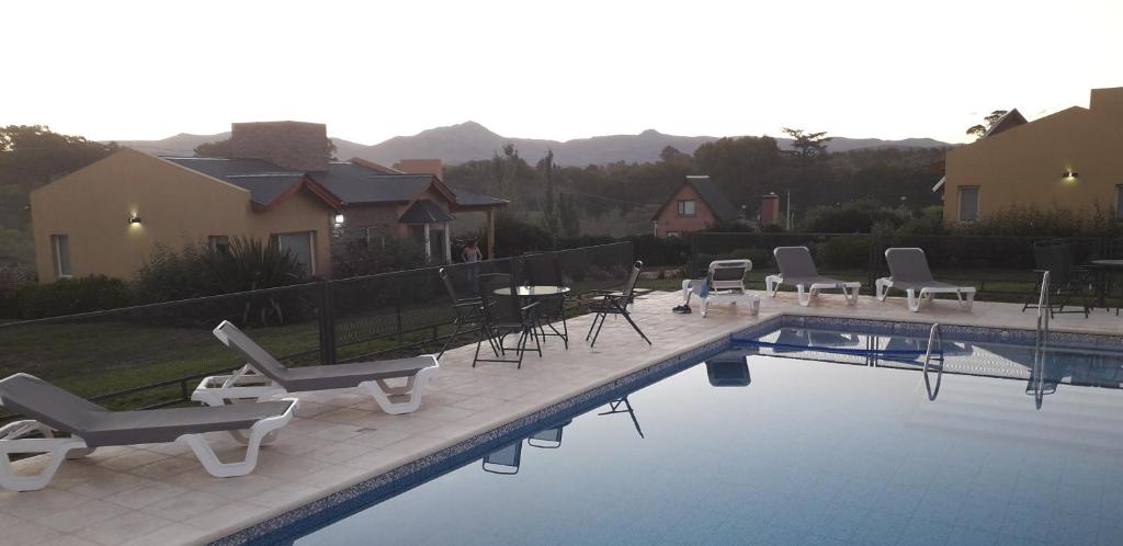 a swimming pool with lounge chairs and a table at Cabañas De Los Tios in Sierra de la Ventana