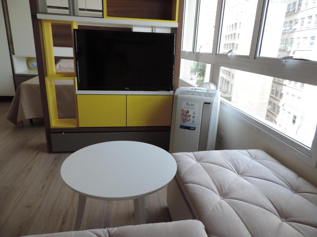 uma sala de estar com uma televisão, um sofá e uma mesa em Apartamento mobiliado novo Metrô Luz em São Paulo