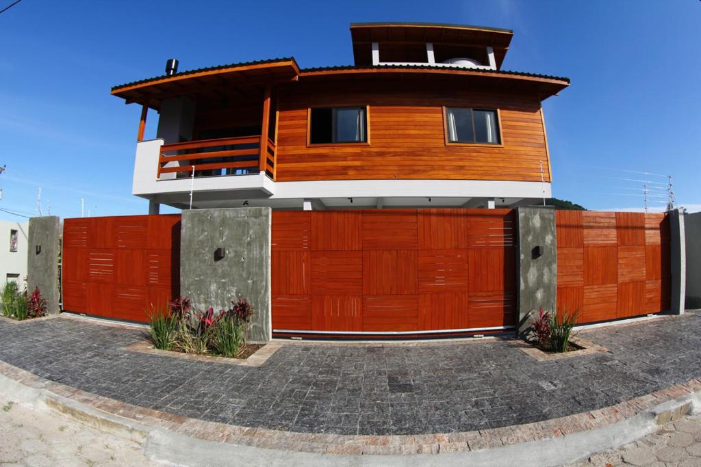 a house with a red fence and a building at Barra Holiday Apartamentos in Florianópolis