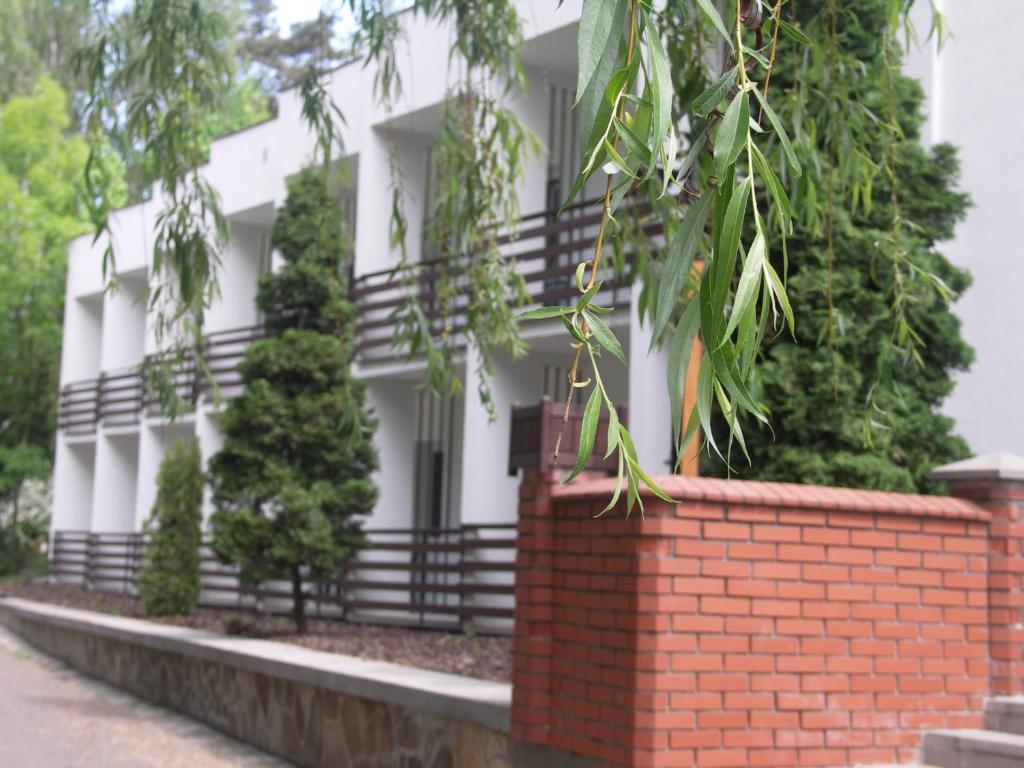 a white building with a brick wall and trees at Motel Strzeszynek in Poznań