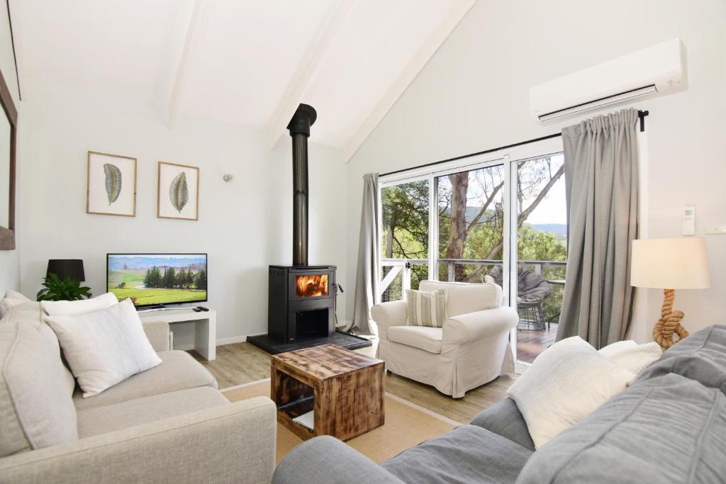 a living room with a couch and a fireplace at Treetops - Three bedroom home with great views, in the village! in Kangaroo Valley