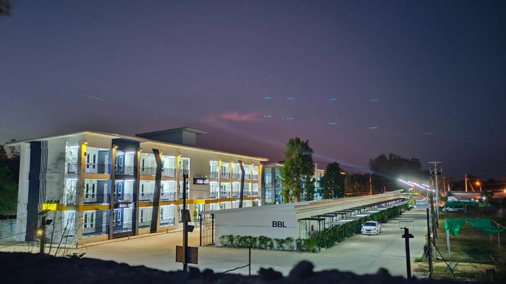 un edificio con un estacionamiento delante de él por la noche en โรงแรมบาบาราย, en Sisaket