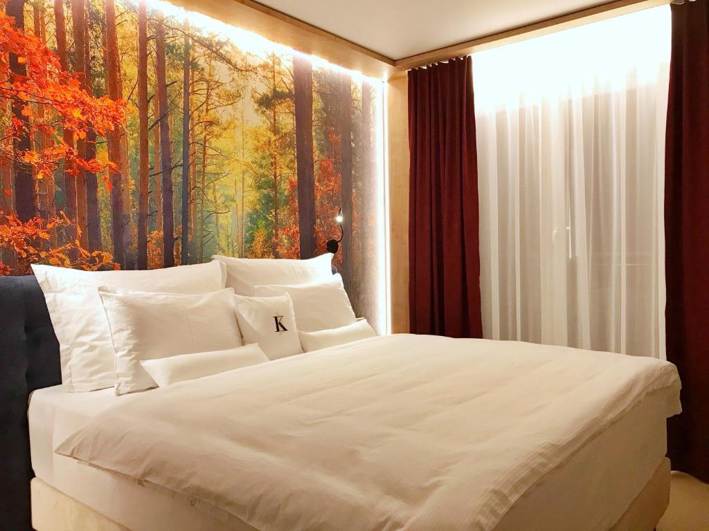 a bedroom with a white bed with a painting on the wall at Wellness penzion Lázně Kvilda in Kvilda