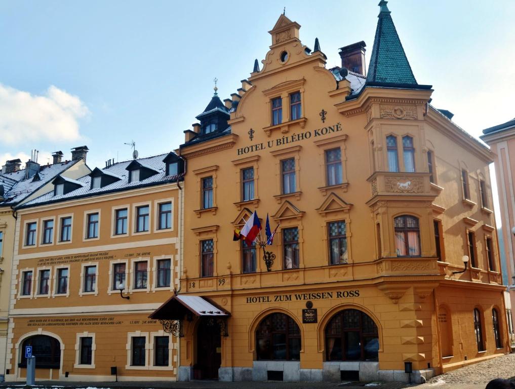 a large yellow building with a sign on it at Hotel U Bílého koně in Loket