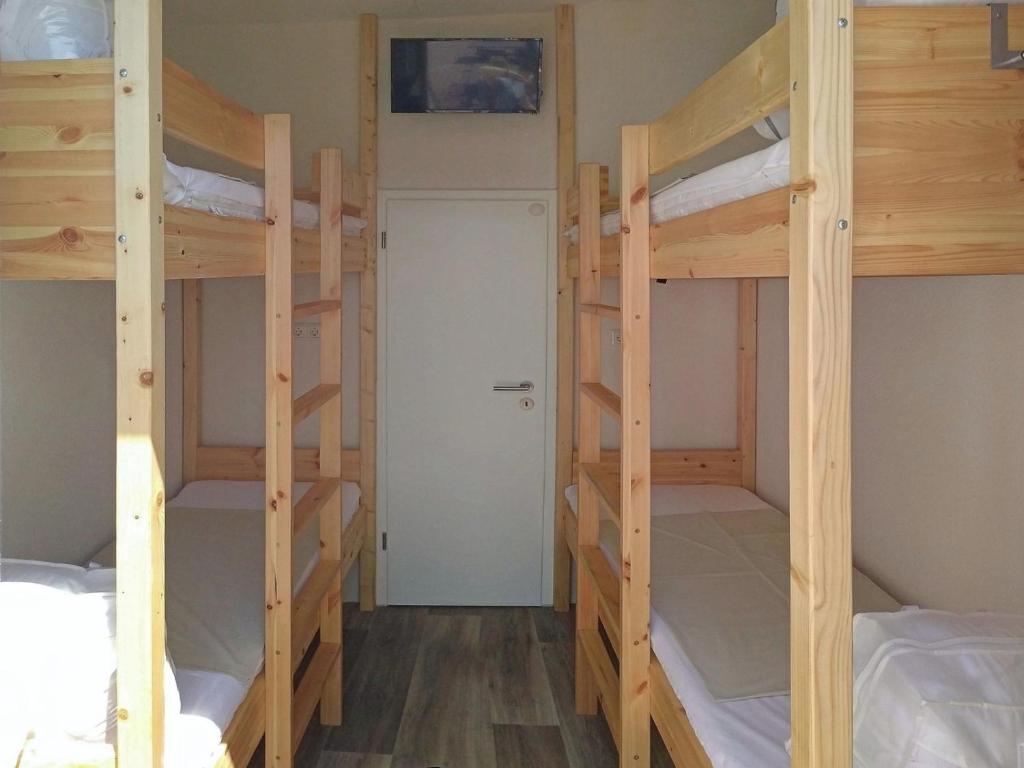 Zimmer mit 3 Etagenbetten und einer Tür in der Unterkunft Mola Land-Kajüten in Breege