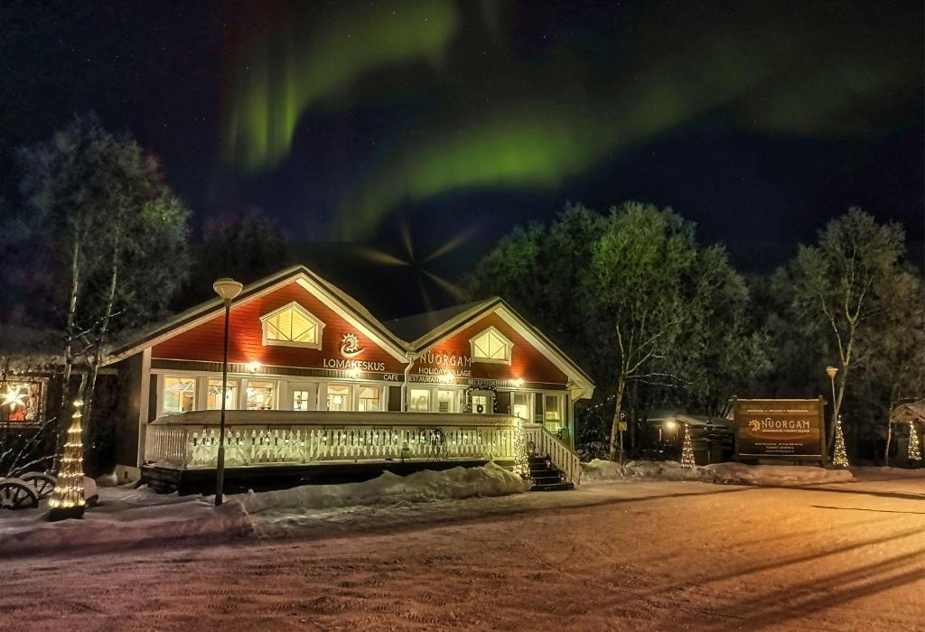 una casa con la aurora en el cielo en Holiday Village Nuorgamin Lomakeskus, en Nuorgam