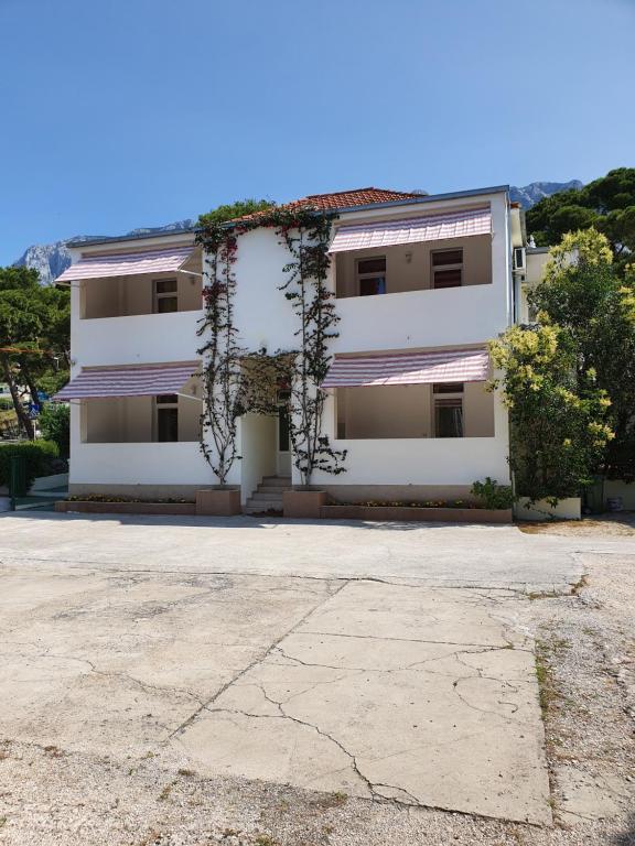 a white house with vines growing on it at Studio Apartments Marija with private parking in Makarska