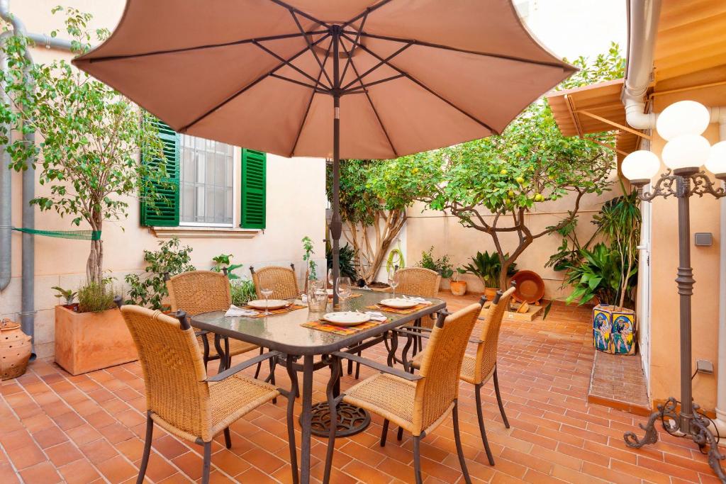 een patio met een tafel en stoelen en een parasol bij Can Duran in Palma de Mallorca