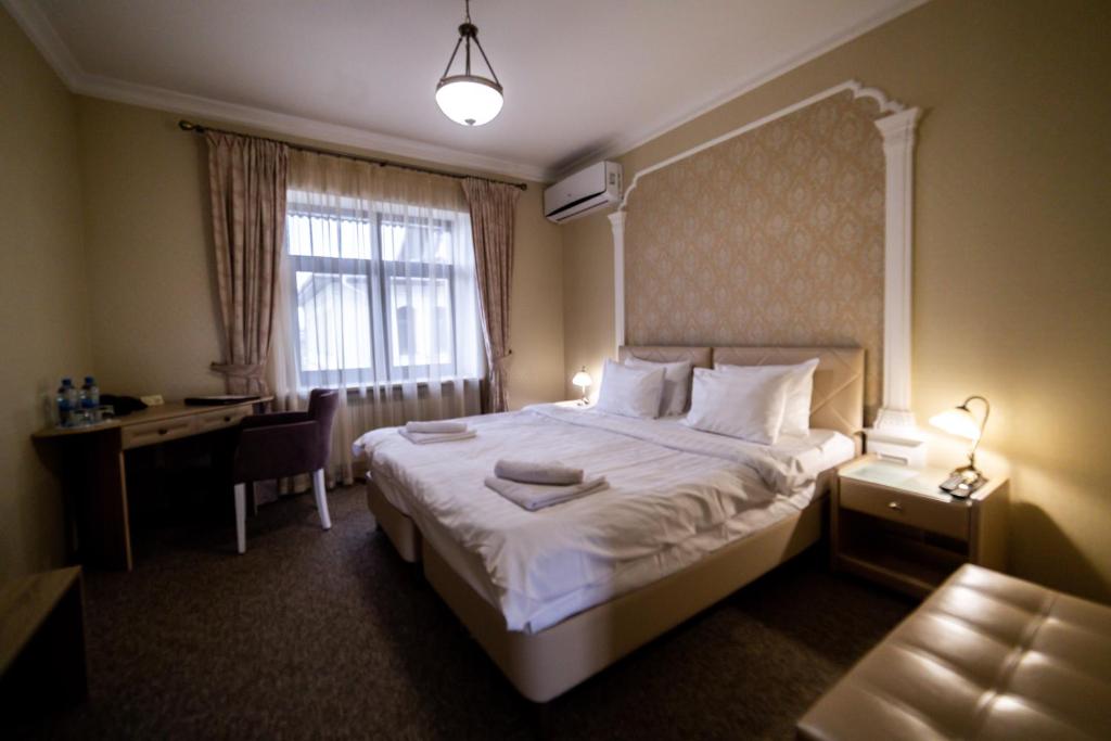 スーズダリにあるMedniy Dvorのベッド、デスク、窓が備わるホテルルームです。